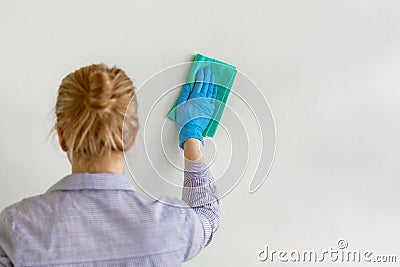 Employee hand in blue rubber protective glove wiping wall from dust with dry rag. Commercial cleaning company Stock Photo