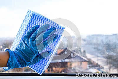 Employee hand in rubber protective glove with micro fiber cloth wiping window from dust. copy space, General cleaning Stock Photo