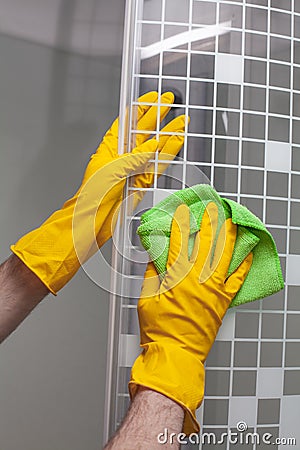 Employee hands in rubber protective gloves with rag washing and polishing a shower cabin doors. Cleaning concept Stock Photo