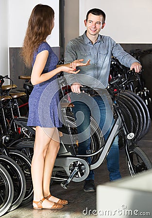 Employee helping adult guy to select bike at rental agency Stock Photo
