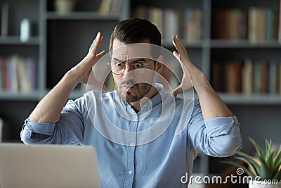 Employee looks at laptop feels angry having problems with device Stock Photo