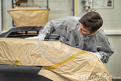 An employee of the paint shop of the automobile plant prepares bumpers for painting Stock Photo