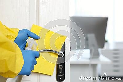 Employee in protective suit and gloves sanitizing door knob indoors, closeup. Medical disinfection Stock Photo