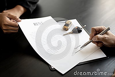 An employee of the rental car company submits a car rental agreement. Stock Photo