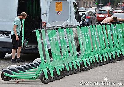 An employee of the rental service unloads electric scooters on the sidewalk in the city center Editorial Stock Photo