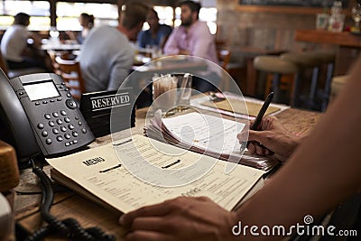 Employee at a restaurant writing down a table reservation Stock Photo