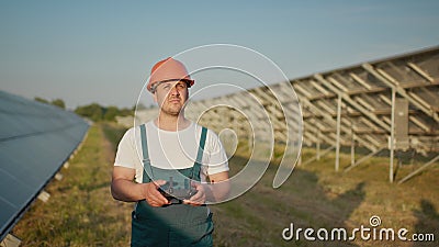 An employee of a solar power plant talks on a walkie-talkie while his colleagues and an investor check the solar power Stock Photo