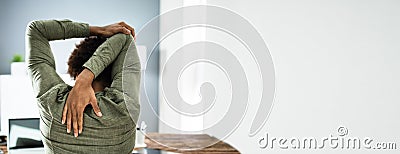 Employee Stretching At Office Desk Stock Photo