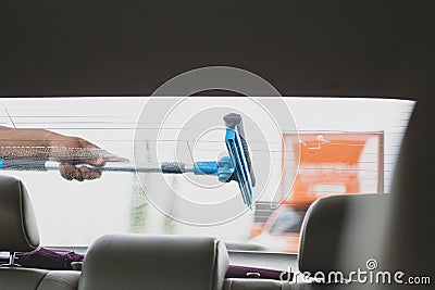 Employee using sponge to clean a car windscreen at gas station. Stock Photo