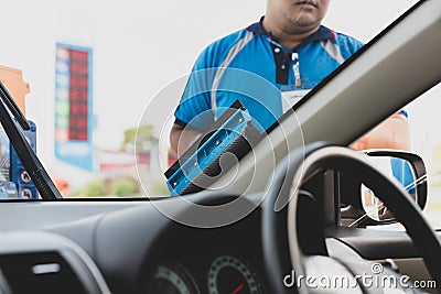 Employee using sponge to clean a car windscreen at gas station. Stock Photo