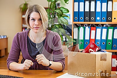 Employee woman is absolutely furious about lost her job, sitting in workplace with carton box with things Stock Photo
