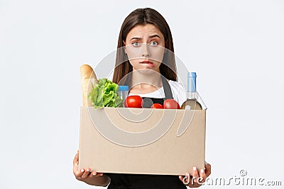 Employees, delivery and online orders, grocery stores concept. Puzzled and indecisive cute saleswoman, cashier holding Stock Photo