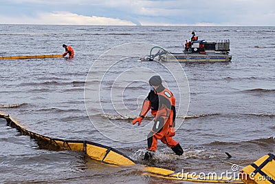 Employees of the environmental service clean up after low tide on the coast Gulf of Finland remove garbage, oil spills, harmful Editorial Stock Photo