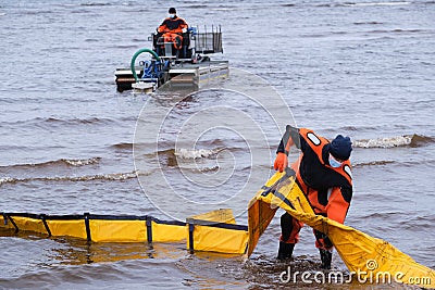 Employees of the environmental service clean up after low tide on the coast Gulf of Finland remove garbage, oil spills, harmful Editorial Stock Photo