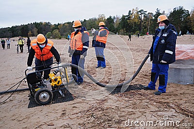 Employees of the environmental service clean up after low tide on the coast Gulf of Finland remove garbage, oil spills, harmful Editorial Stock Photo