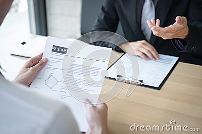 Employer or recruiter holding reading a resume during about colloquy his profile of candidate, employer in suit is conducting a Stock Photo