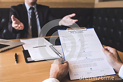 Employer or recruiter holding reading a resume during about his profile of candidate, employer in suit is conducting a job Stock Photo