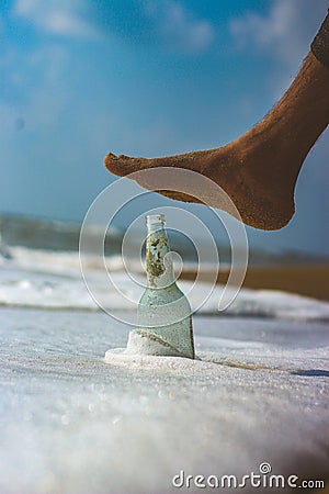 Emply bottle on the beach sand with water waves Stock Photo