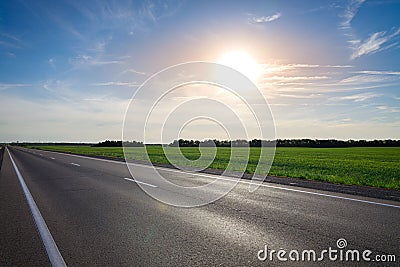 Empty asphalt highway against the bright sun at sunset Stock Photo