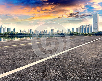 Empty asphalt pavements and modern urban landmarks in the setting sun Stock Photo