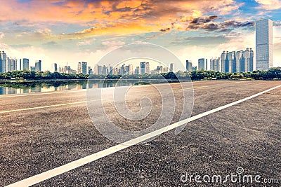 Empty asphalt pavements and modern urban landmarks in the setting sun Stock Photo