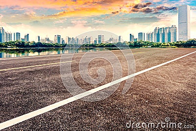 Empty asphalt pavements and modern urban landmarks in the setting sun Stock Photo