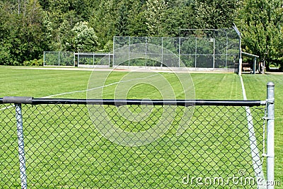 Empty baseball or softball diamond from the back fence and foul line looking towards the grass and trees in Whistler, British Stock Photo