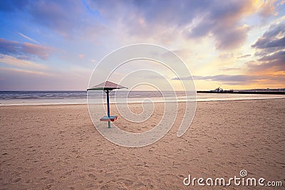 Empty beach with lonely umbrella at sunset Stock Photo