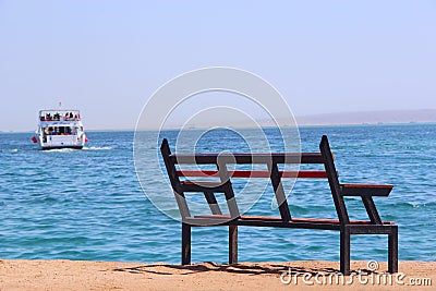 Empty bench near sea and shipped ship. Loneliness. Departure of ship. Bench near beach Stock Photo