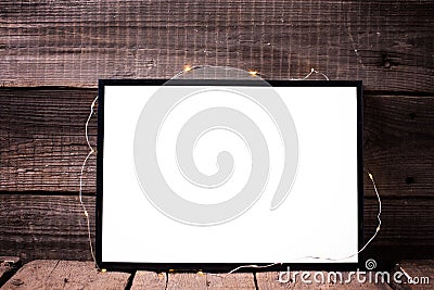 Empty black frame with twinkle light on rustic wooden backg Stock Photo