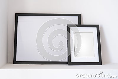 Empty black frames, posters, white canvas, mock up on a white wall, bedroom, gallery template, close up Stock Photo