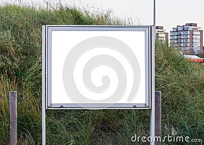 Empty and blank metallic information board to put what ever you want with a green grass hill in the background Stock Photo