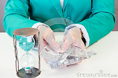Empty blisters in hands and sandclock Stock Photo