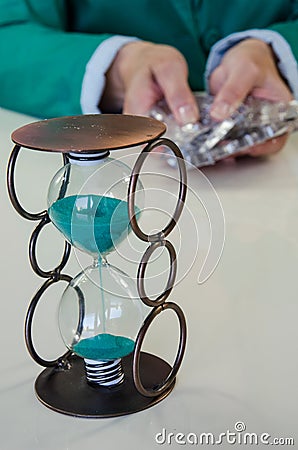 Empty blisters in hands and sandclock Stock Photo