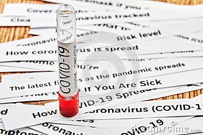 Empty Blood test tube sample for presence of coronavirus COVID-19 on the background of newspaper headline clippings Stock Photo