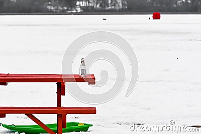 Empty Bottle on Picnic Table by Lake, Sled, Ice Fishing Stock Photo