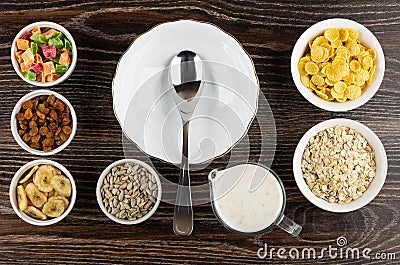 Bowl, spoon and different ingredients for muesli dried fruits, corn flakes, oatmeal, sunflower seeds, banana chips, yogurt on Stock Photo