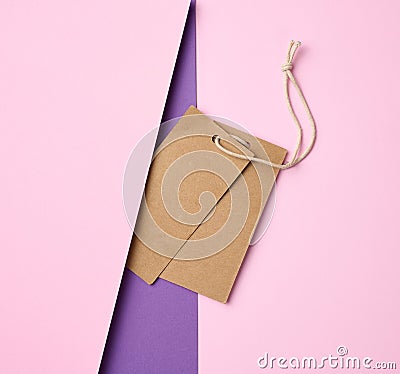 Empty brown tags on a rope, pink background. Price template Stock Photo