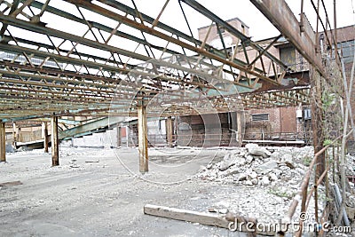 an empty building with several metal structures and rusty beams, including some broken down Stock Photo