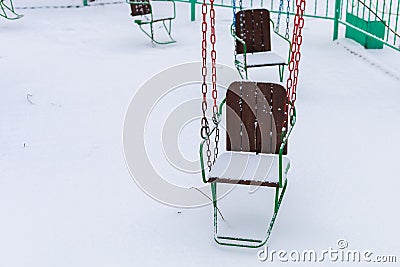 Empty carousels for children covered with snow in winter. Background with selective focus and copy space Stock Photo