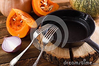 Empty cast iron pan with two forks on wood slab decorated with r Stock Photo
