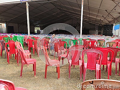 Empty chairs of red green and brown color lying in the tent disorganised. Stock Photo