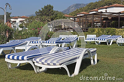 Empty chaise lounges with mattresses on the lawn at the hotel in Stock Photo