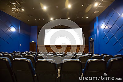 Empty cinema auditorium with empty white screen. Empty rows of blue theater or movie seats Stock Photo