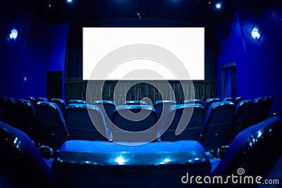 Empty cinema auditorium with empty white screen. Empty rows of theater or movie seats. Blue toned Stock Photo