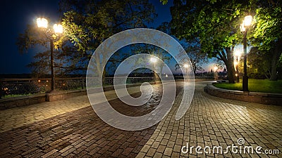 Empty city park landscape at the late evening or night with lit lightposts and brick road Stock Photo