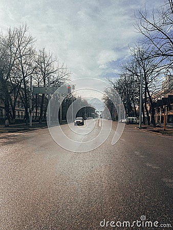 Empty city street with snow-covered trees, distant mountains, and blue sky Stock Photo