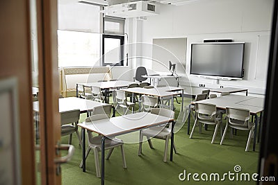 An empty classroom in a primary school with white desks and chairs, seen from doorway Editorial Stock Photo