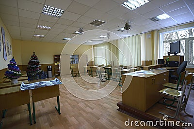 Empty classroom of a school: desks, teacher`s drawer, decorated Christmas trees Editorial Stock Photo