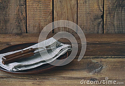 Empty clay plate, cutlery, napkin on wooden background. Table setting. Side view. Rustic style. Copy space. Mock up, concept for Stock Photo
